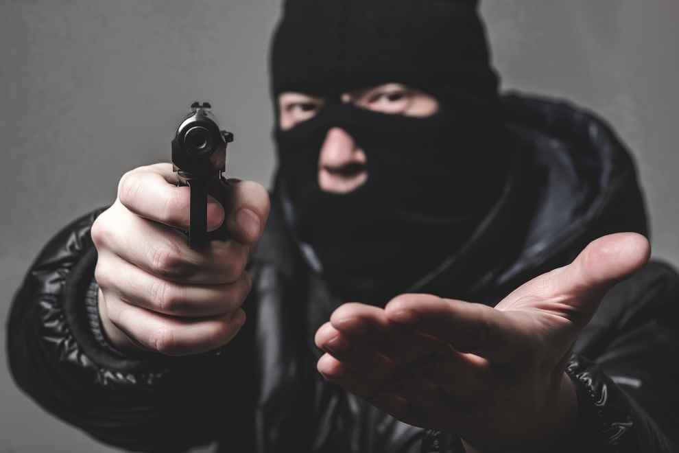 Le malfaiteur vêtu de noir et cagoulé  est entré dans le bar-tabac en exhibant une arme de poing - Illustration © iStock